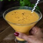 holding a glass with Indian Mango drink