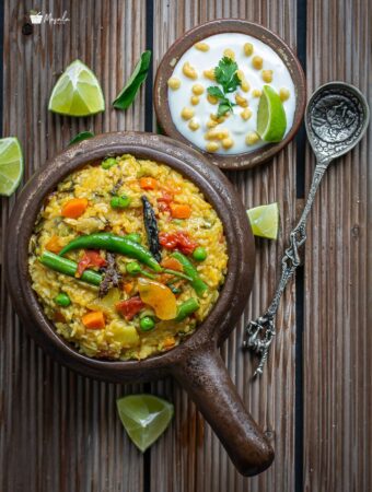 Khichdi served in a bowl with raita one the side