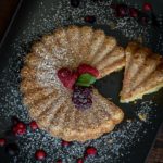 Top view of sliced Eggless Vanilla Cake dusted with some powdered sugar.