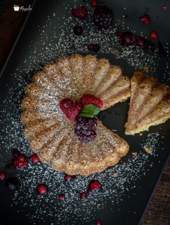 Top view of sliced Eggless Vanilla Cake dusted with some powdered sugar.