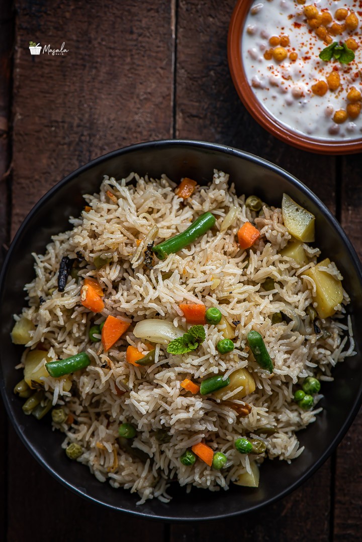 To view of Instant Pot Vegetable Biryani served in a black bowl with Boondi Raita on the side.
