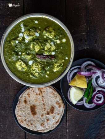 Palak paneer curry served with roti and onions one the side.