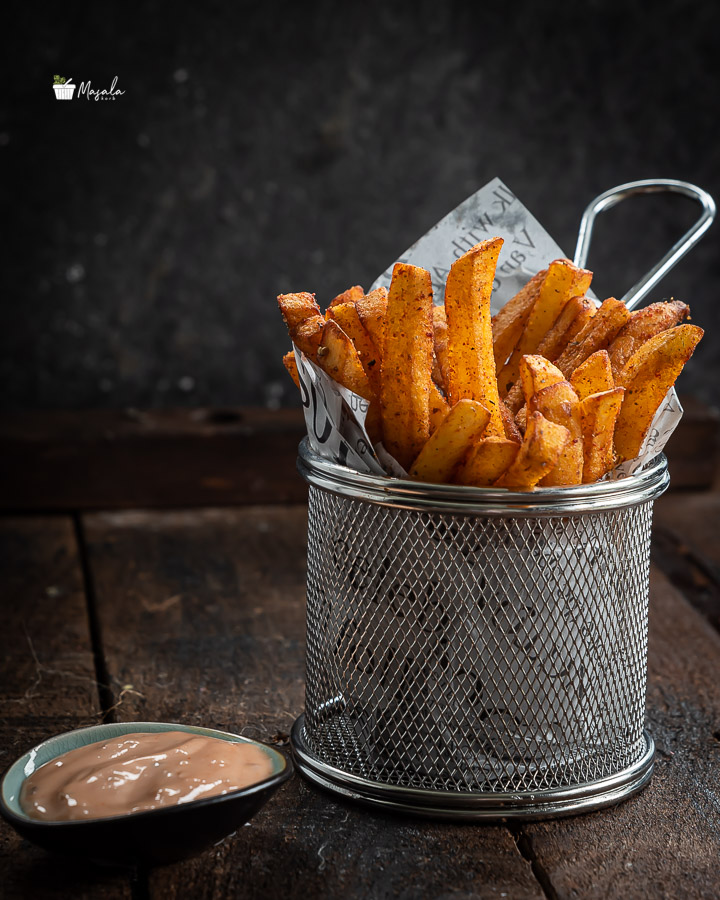 Crispy Masala French Fries served in a mesh tin.