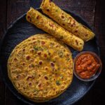 Gujarati Methi Thepla served on a black plate with mango pickle